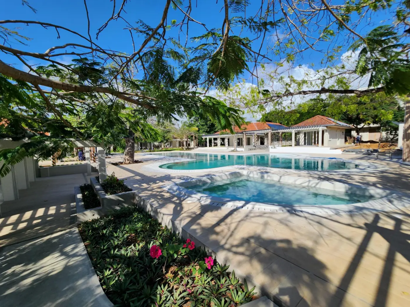 Main pool and plunge pool under flame trees, with the villas beyond, at Maya Ilai
