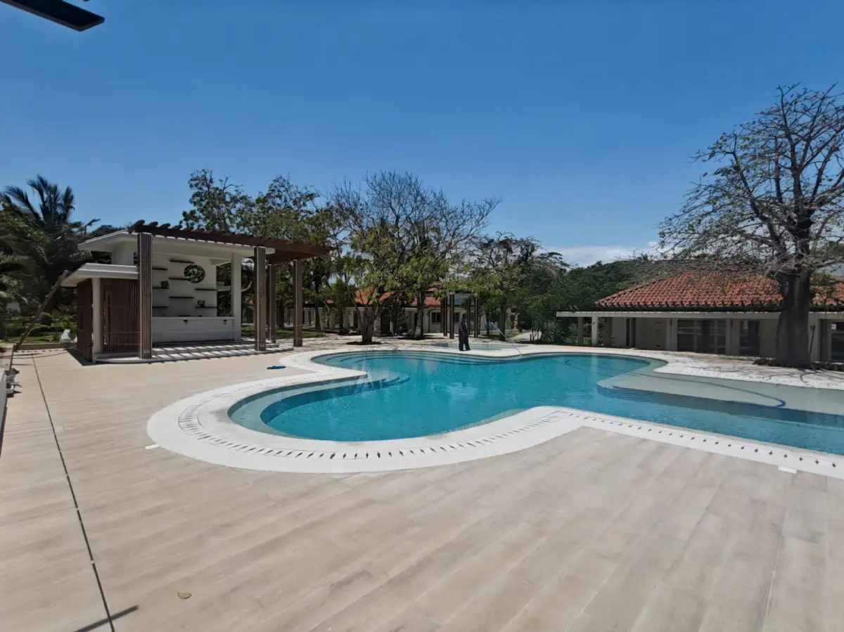 Curved main pool with a timber deck and pergola bar at Maya Ilai
